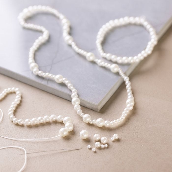 Halsband och armband med pärlemorskimrande vita pärlor