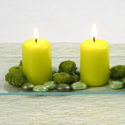 Limefärgade blockljus och dekostenar på glasfat