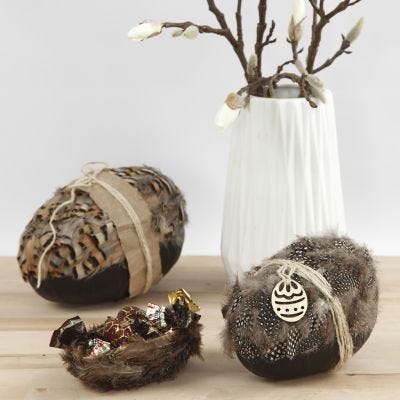 Tvådelade påskägg dekorerade med naturfjädrar