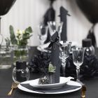 Bordsdukning och bordsdekoration i svart med pappersblommor, ballonger, servetter vikta som torn och bordskort.