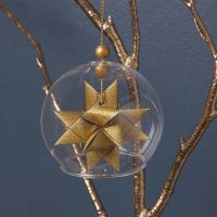 Glasklocka med en flätad guldstjärna på insidan